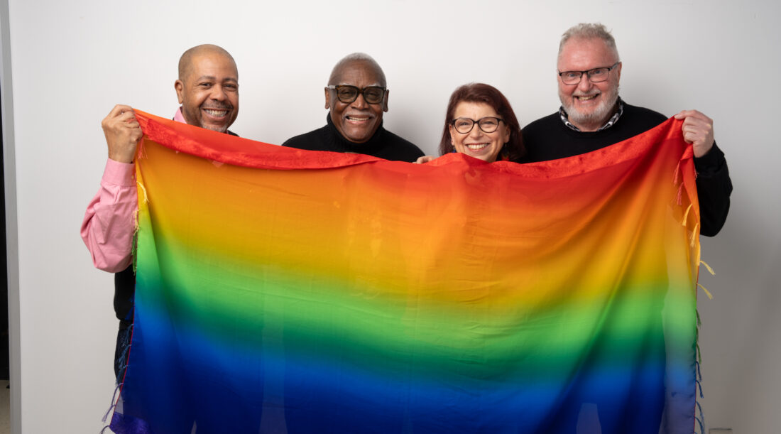 A group of people hold up a rainbow pride flag