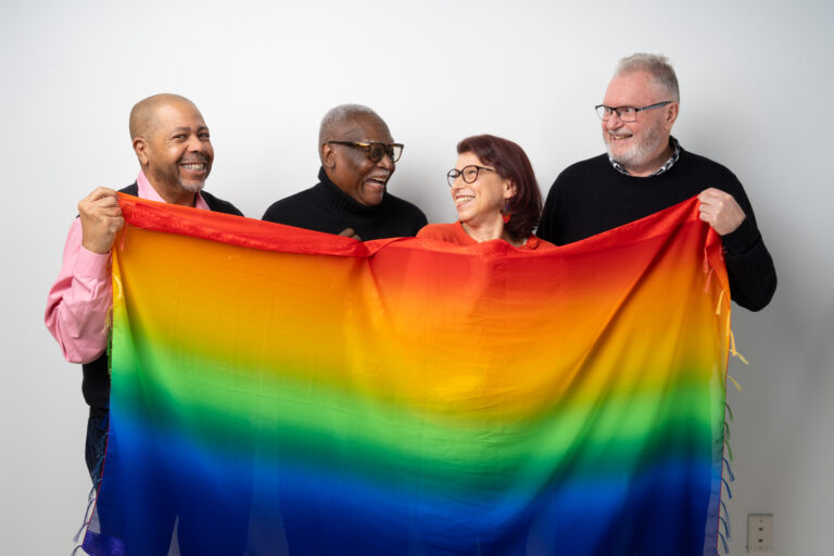 Four people holding up a rainbow flag