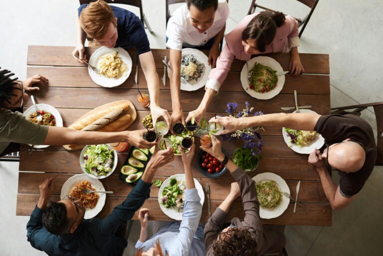Overhead shot of many people toasting glasses over a dinner table