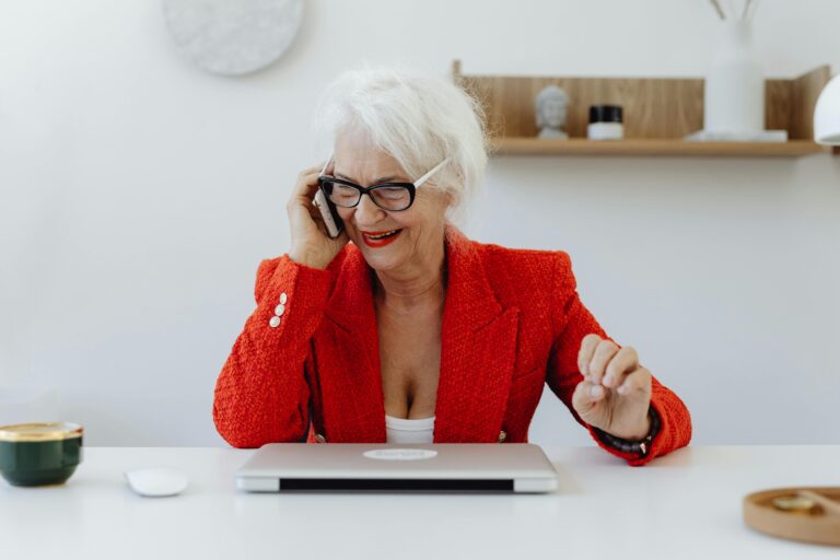 An older woman smiles while holding a phone to her ear