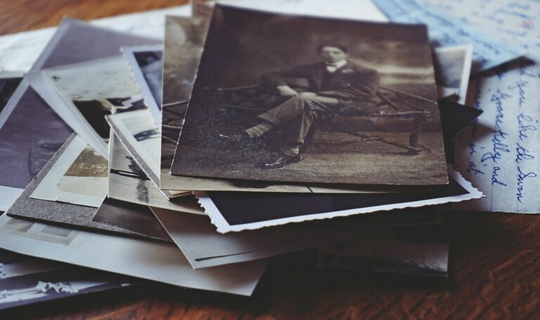 A pile of old letters and photographs, with a black and white photograph of a man in a suit on top